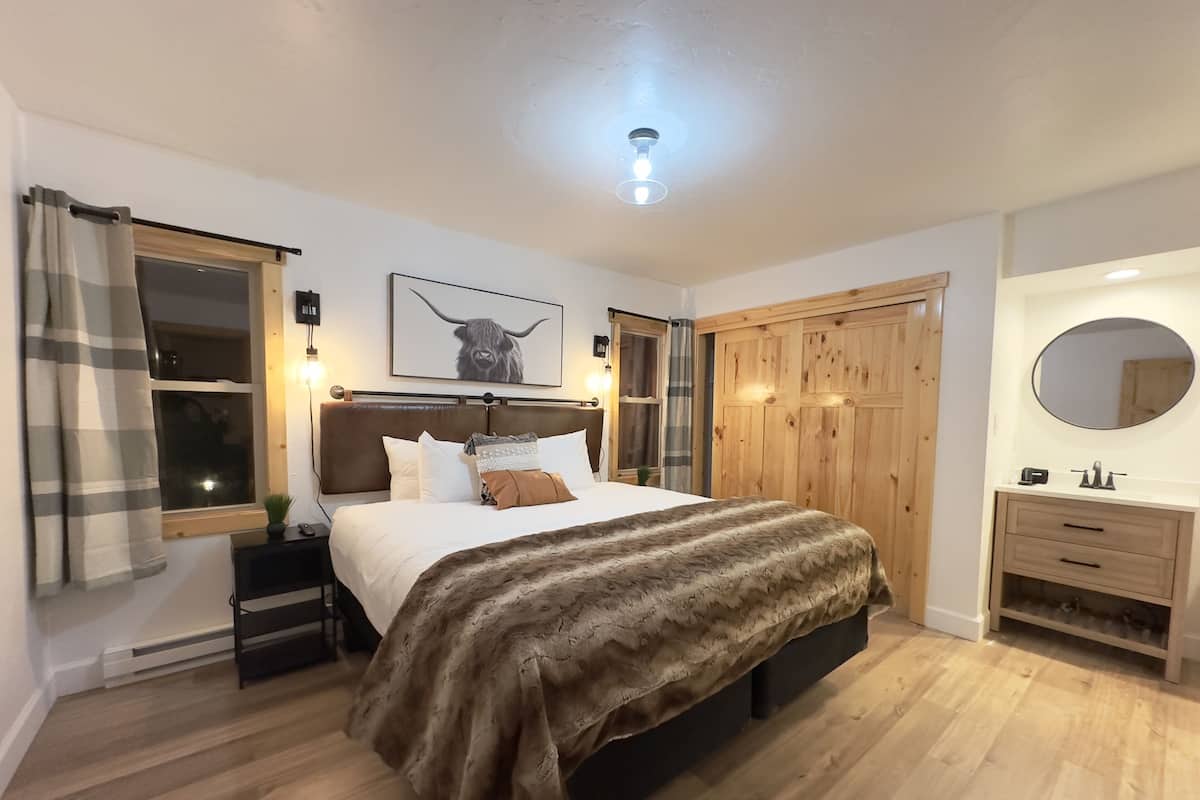 Un dormitorio con cama, mesita de noche, armario de madera y espejo.