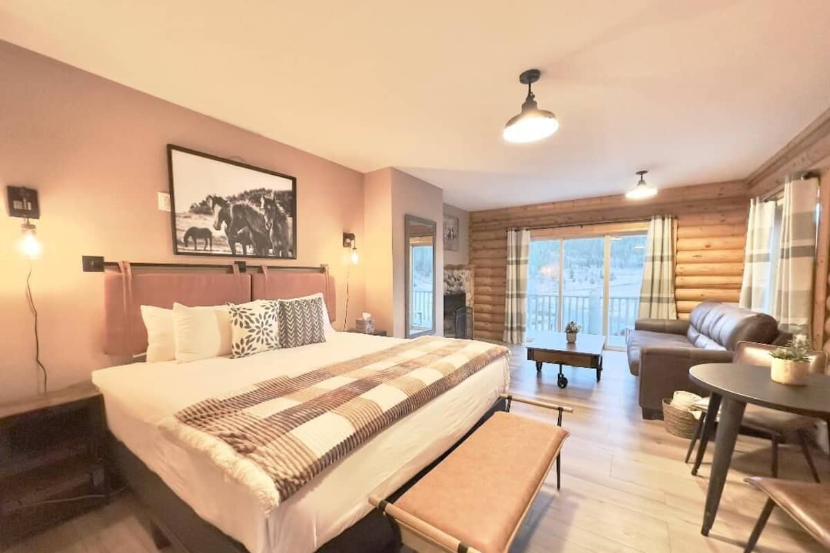 Un dormitorio acogedor con una cama grande, un banco, un sofá y una mesa de comedor.