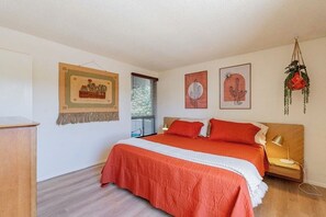 Une chambre à coucher avec un lit, une table de chevet, une lampe et des œuvres d’art murales.