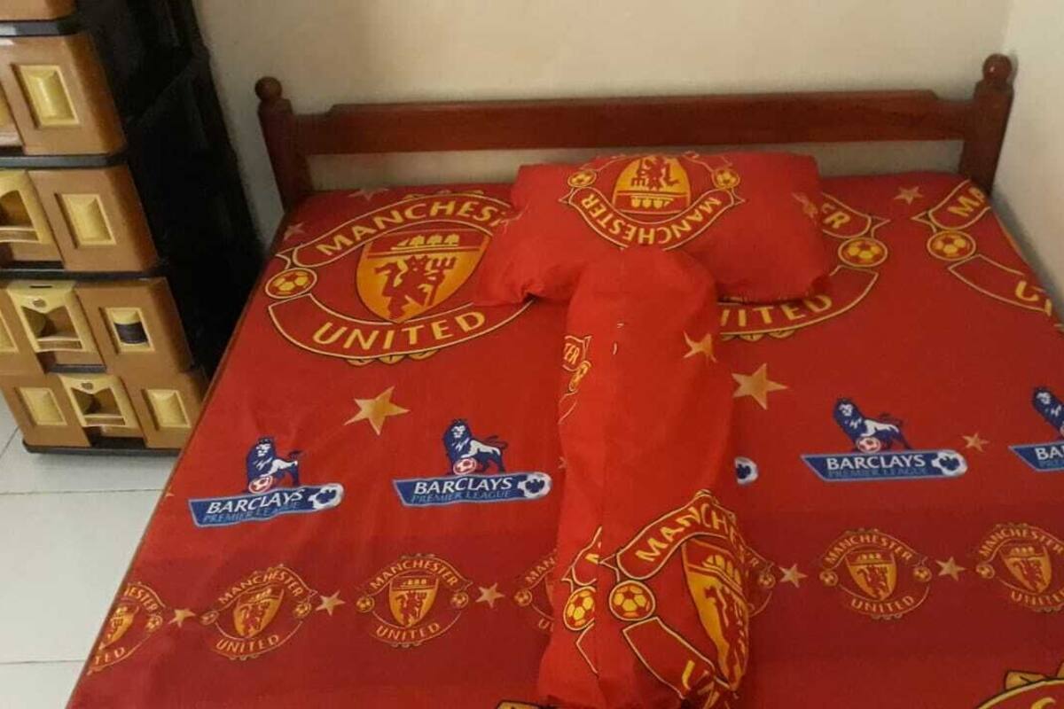 Una cama con funda nórdica y fundas de almohada con motivos del club de fútbol Manchester United.