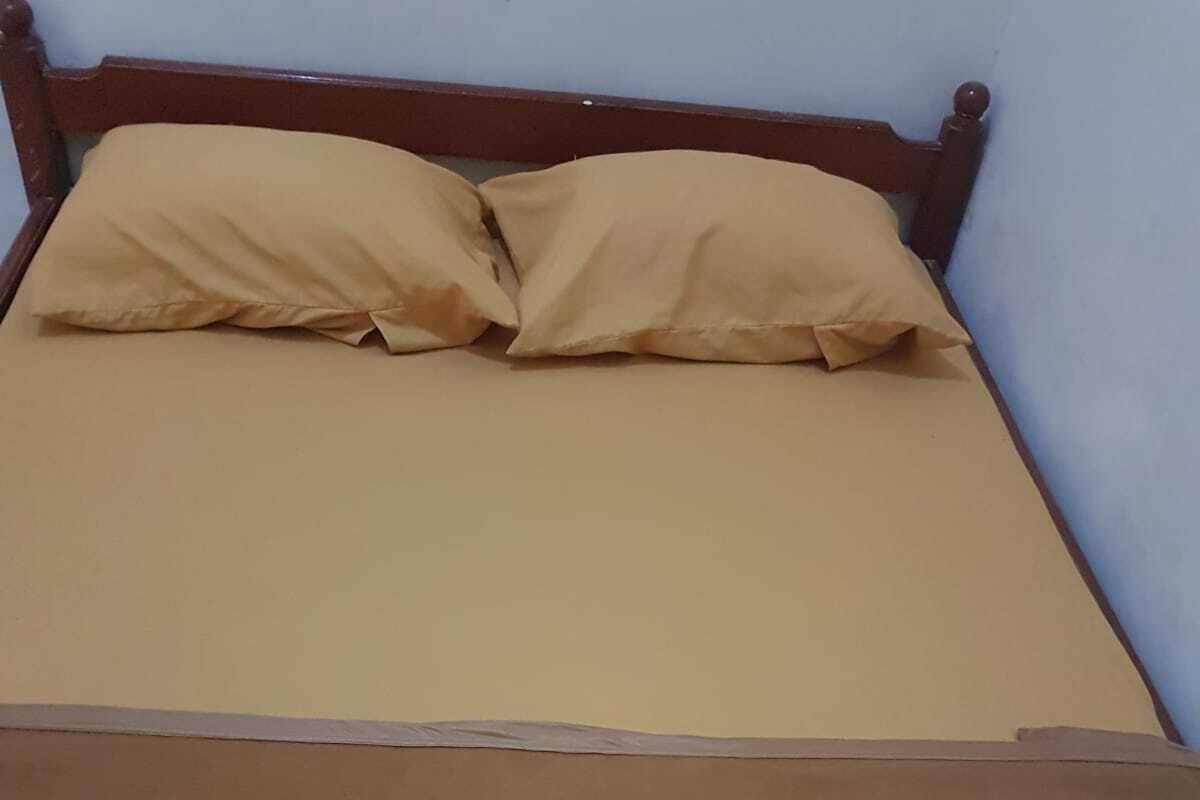 Una cama con cabecera de madera y dos almohadas color beige.