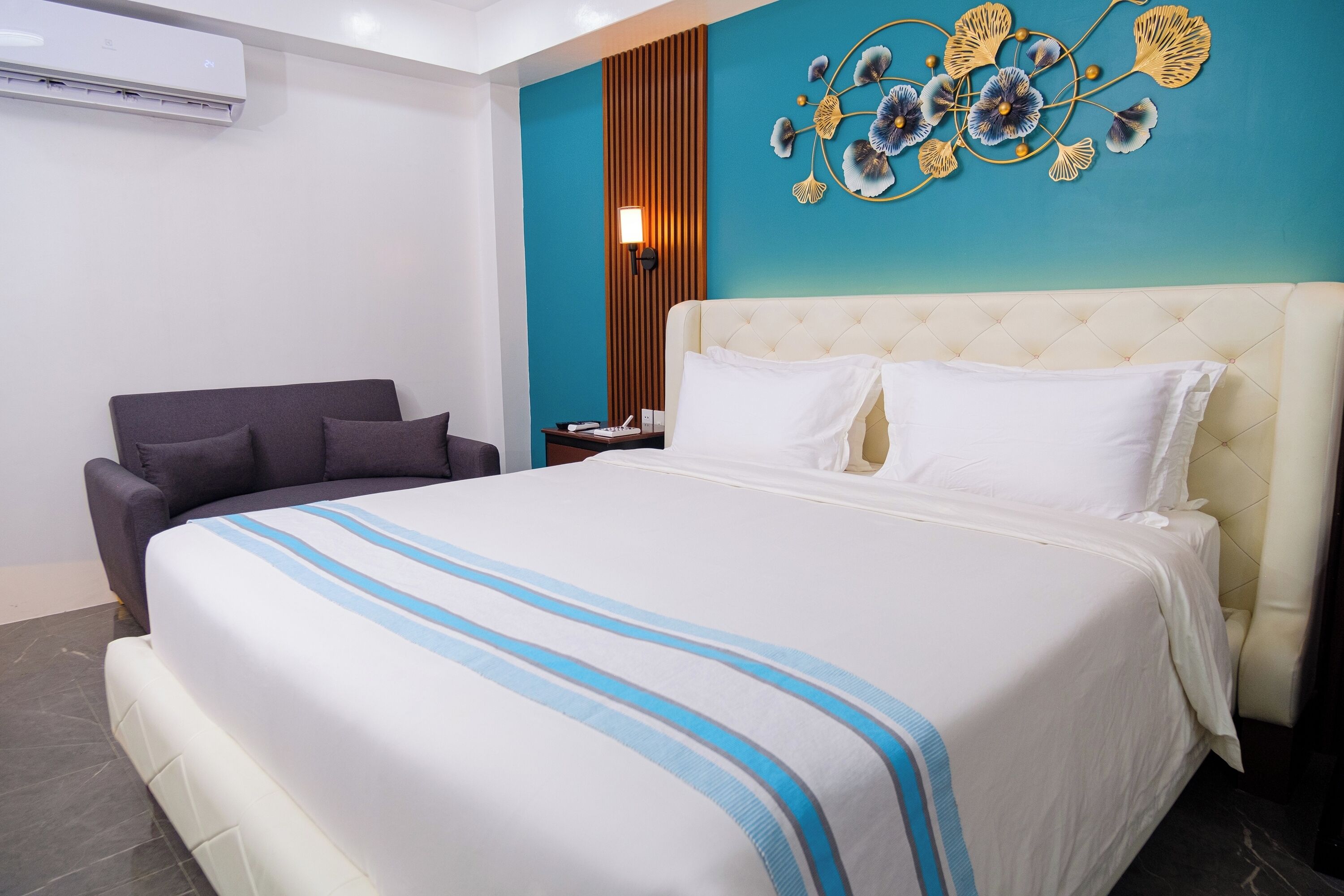 Une chambre d’hôtel avec un grand lit, une chaise, une table de chevet et un élément décoratif mural.