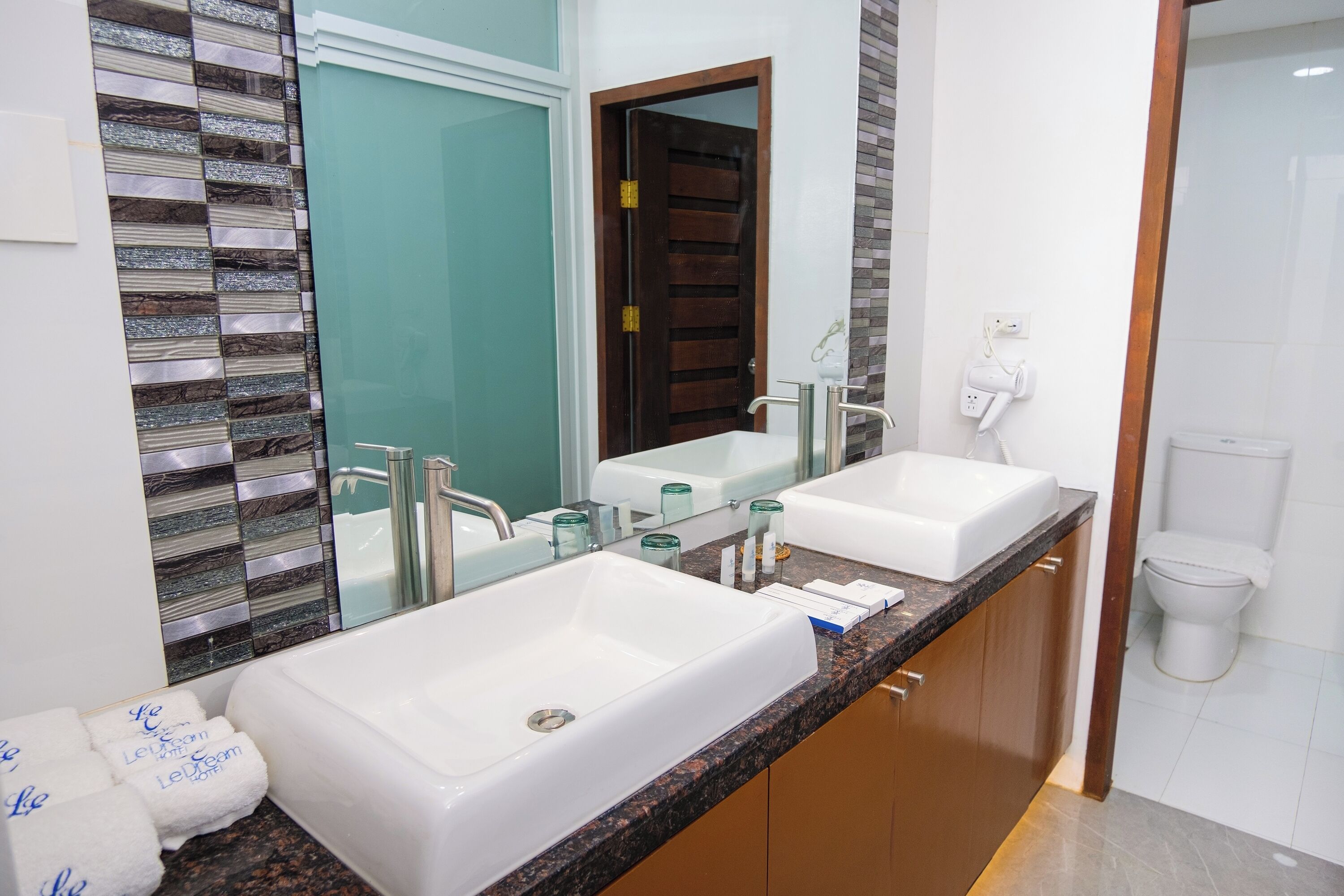 A bathroom with two sinks, a large mirror, and a toilet.