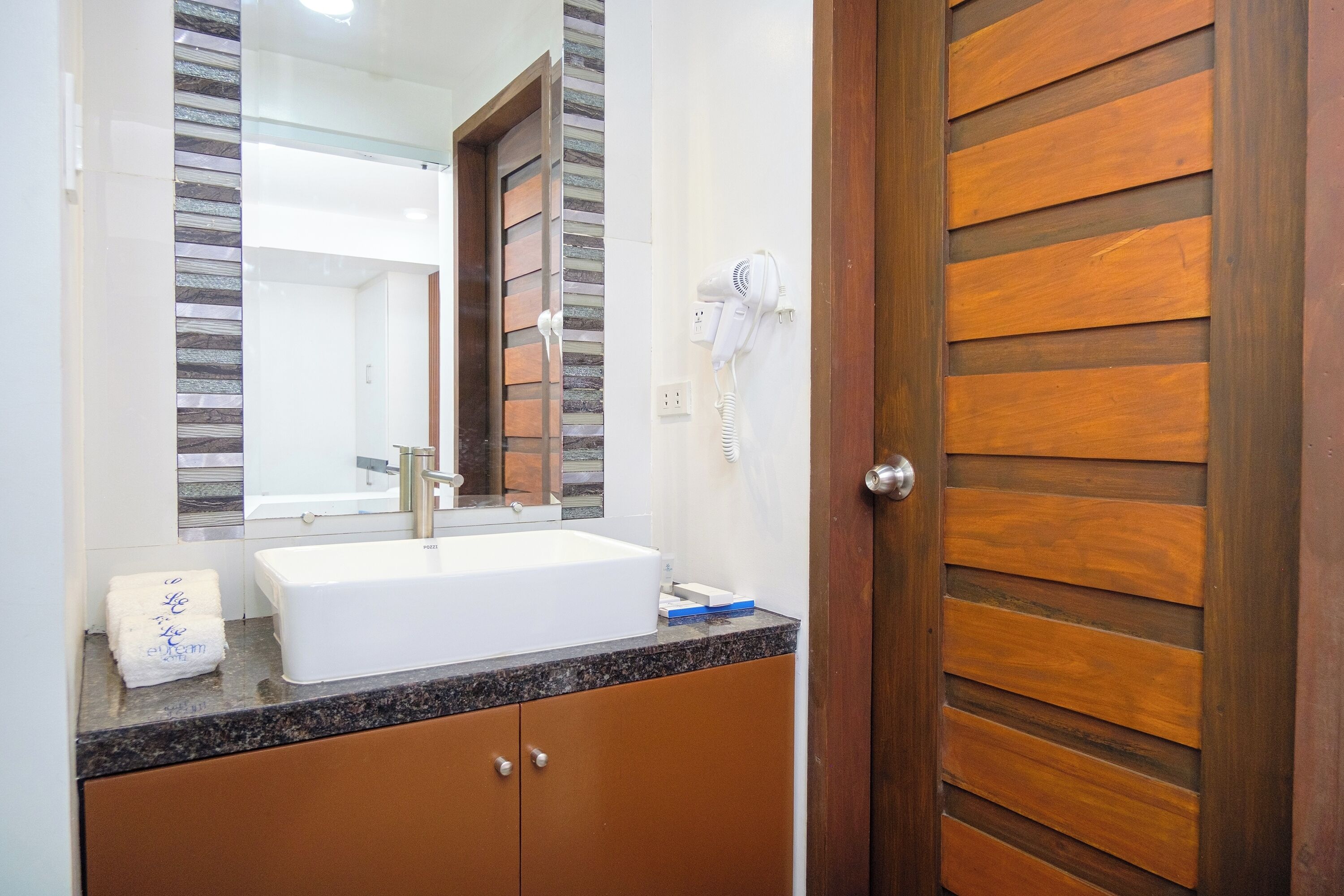 A bathroom with a white sink, a mirror, and a hairdryer on the wall.