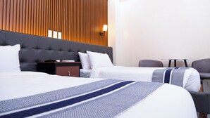 A hotel room with two beds, a wooden panel wall, a small table, and a chair. - Le Dream Hotel near Vigan (Vigan)