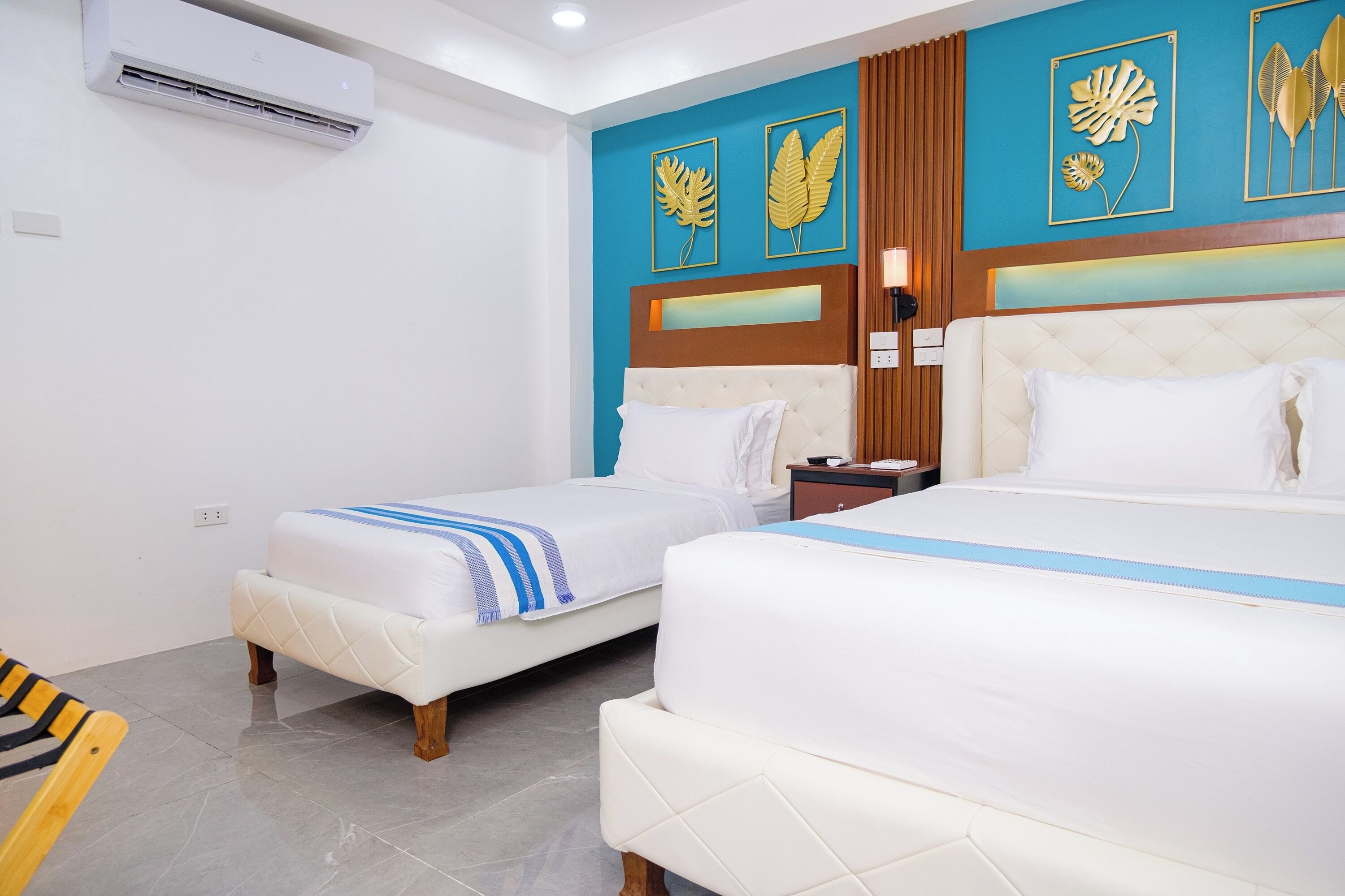 A hotel room with two beds, a wooden headboard, and a wall with decorative leaf artwork.
