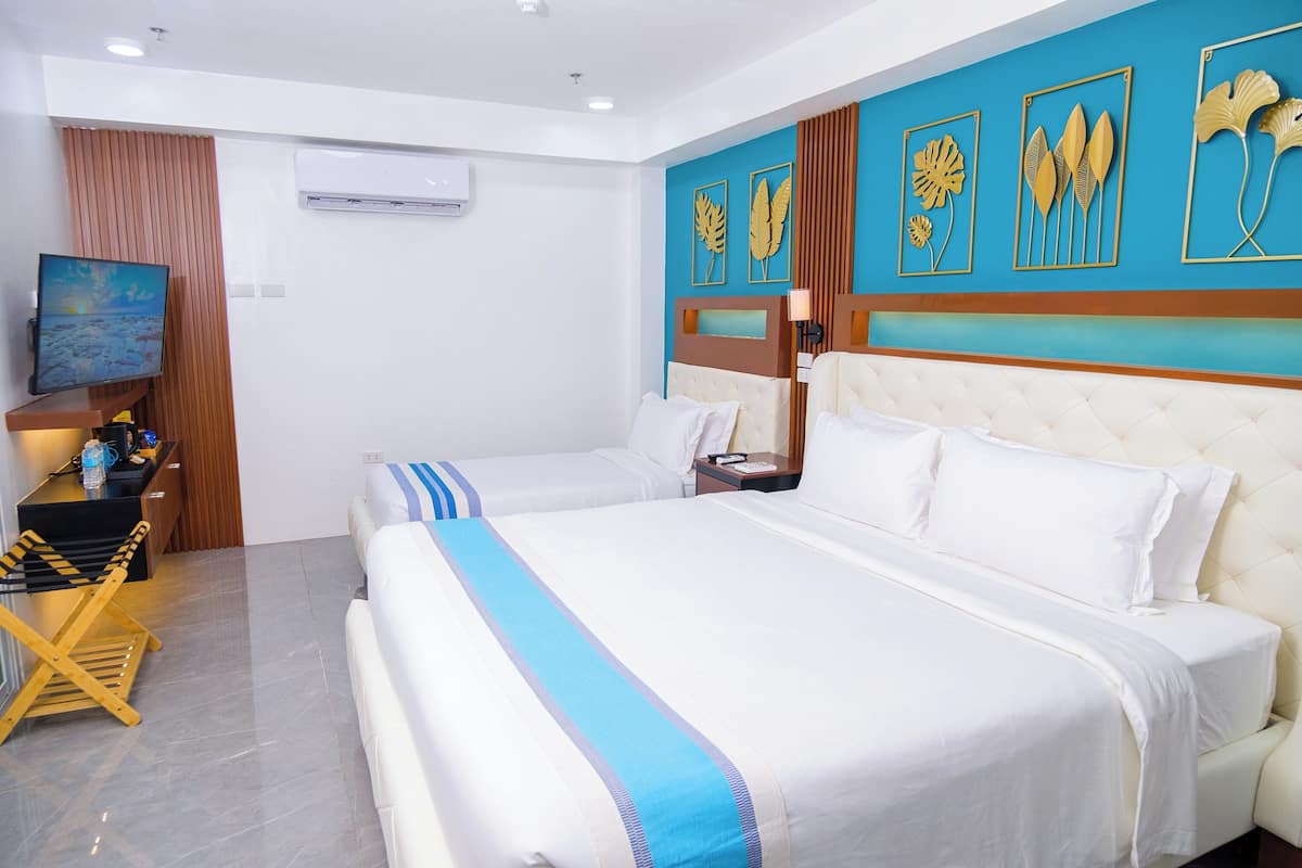 A hotel room with two beds, a TV, a wooden chair, and decorative wall art.