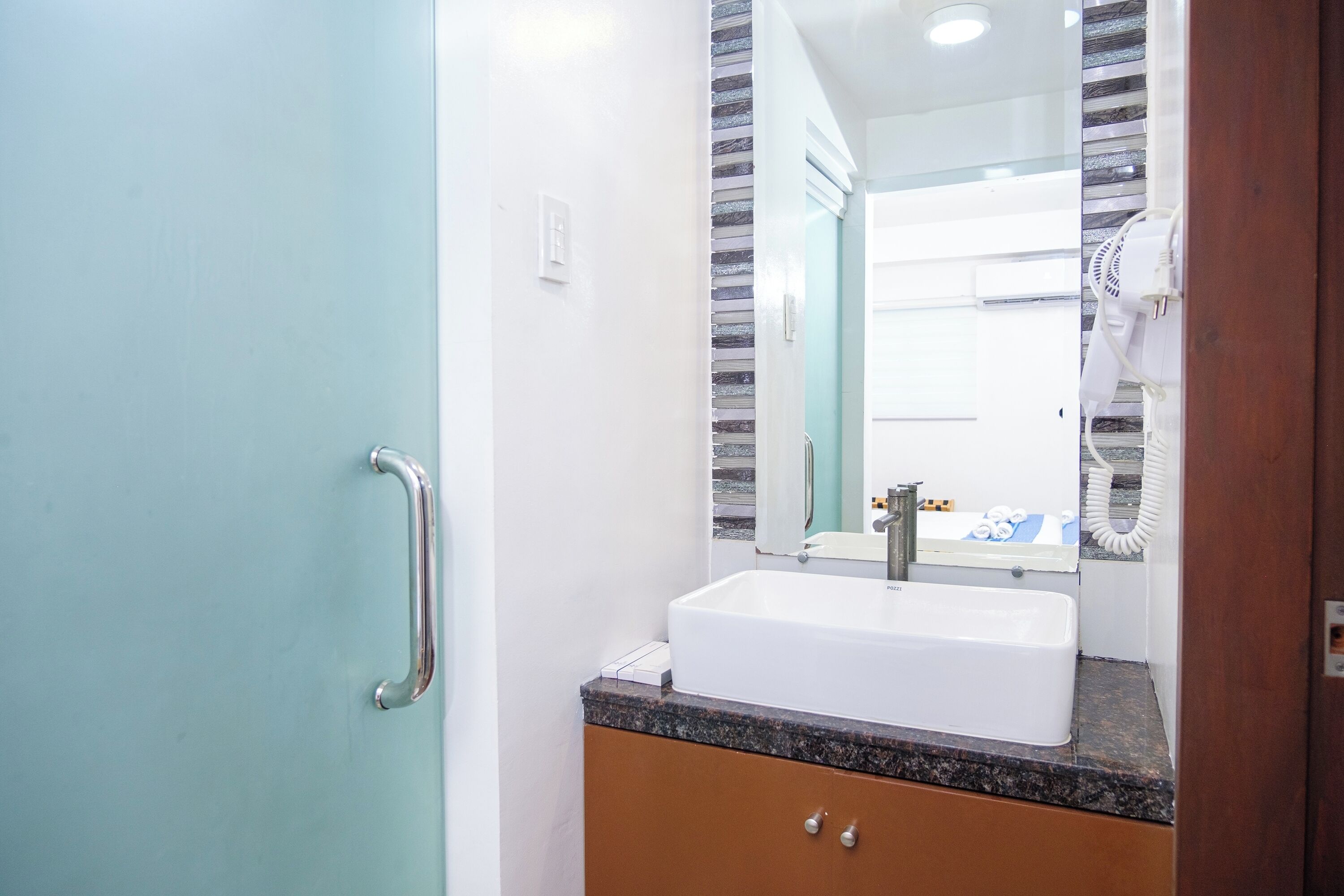 A bathroom with a white sink, a mirror, and a handrail.