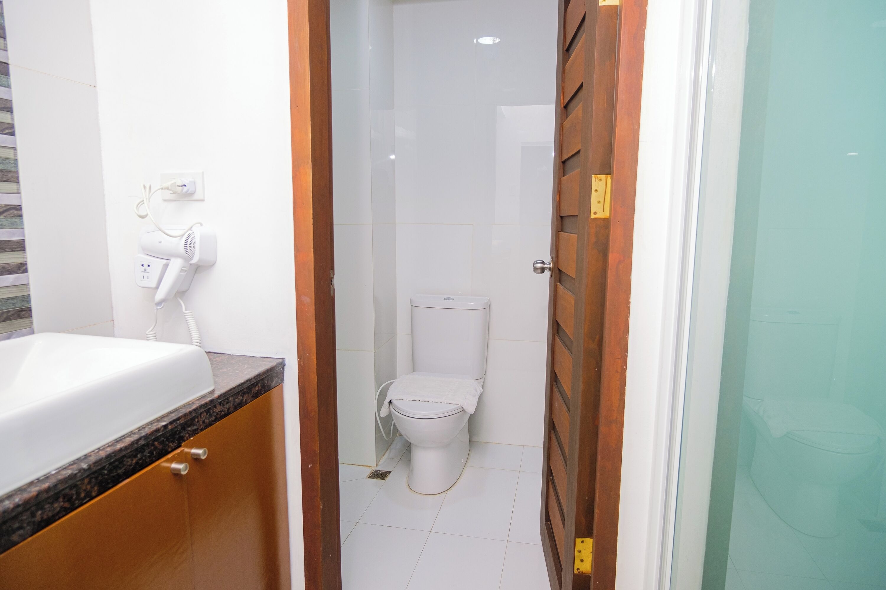 Un baño con un lavamanos blanco, inodoro y zona de ducha.