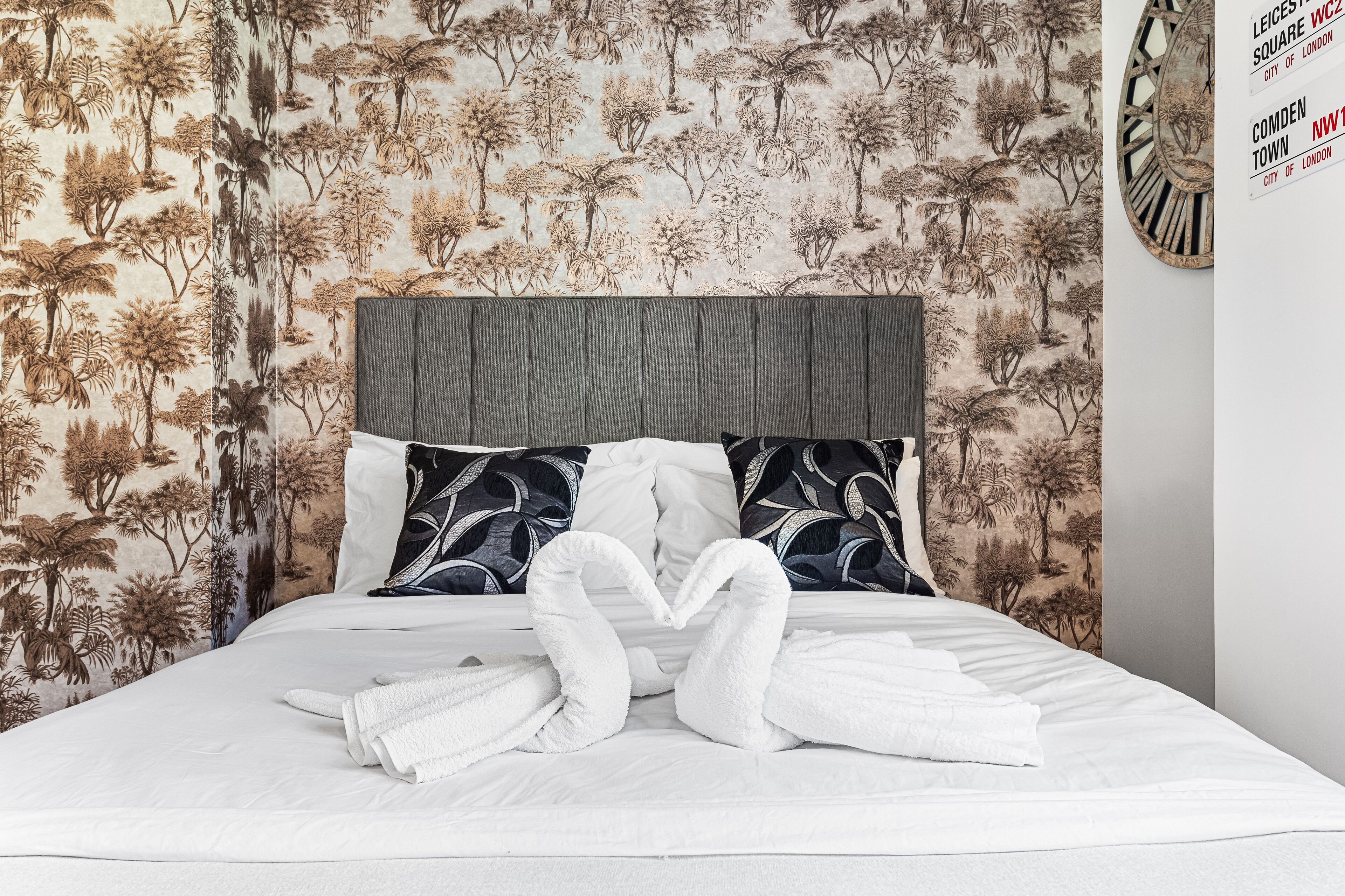 A neatly made bed with white linens and two towels arranged in a heart shape.