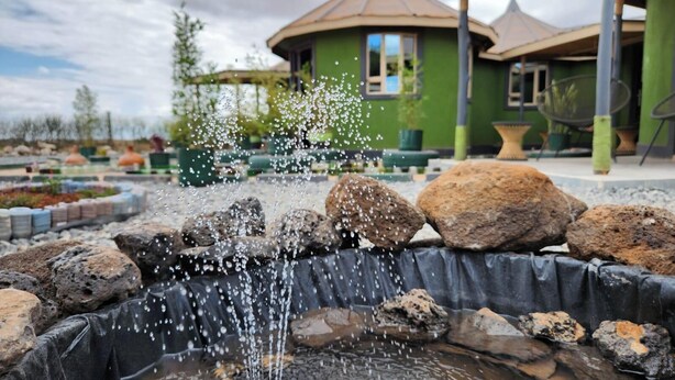 A water feature with rocks and a green building in the background. - Amanya Hut Sleeps 6 with Mountain Views (Risa Amboseli National Park)