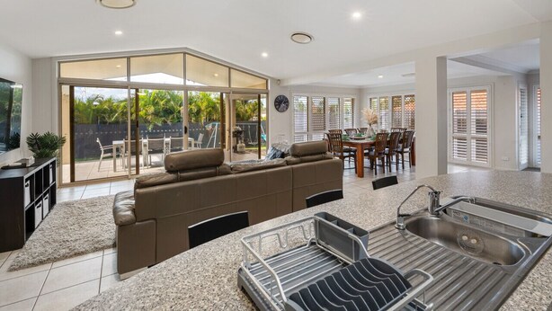 A spacious living area with a large sliding glass door leading to a patio, a kitchen with a granite countertop and stainless steel sink, and a dining area with a table and chairs.