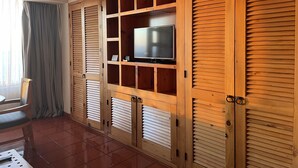Ein Zimmer mit einem Holzkabinett mit mehreren Fächern, einem Fernseher und einem Stuhl.