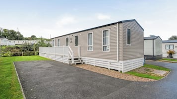 Une maison mobile de plain-pied, dotée d’un porche à l’avant et d’une allée en gravier.