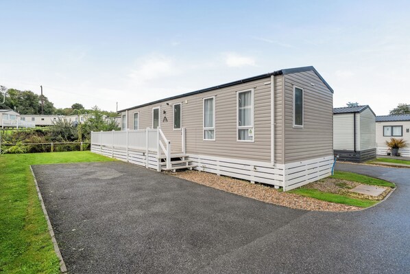 A single-story mobile home with a front porch and a gravel driveway.