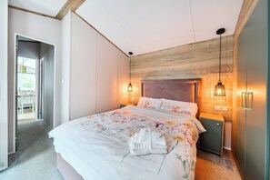 A bedroom with a large bed, bedside lamps, and a view of a dining area.
