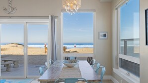 A dining area with a view of the beach, a chandelier, and a large window.