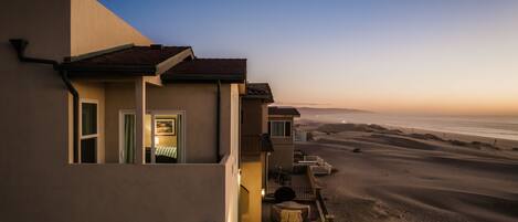 A coastal building with a balcony overlooking the beach.