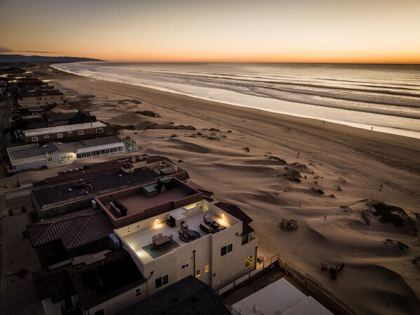 A coastal hotel with multiple buildings, a sandy beach, and a view of the ocean.