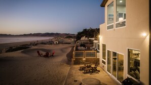 A beachfront property with outdoor seating, a barbecue area, and a view of the ocean.