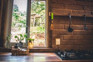 Una cocina con ventana, pared de ladrillo y estufa a gas.