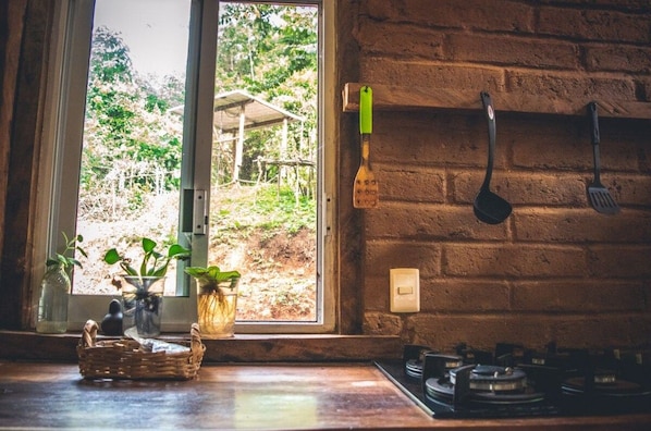 Una cocina con ventana, pared de ladrillo y estufa a gas.