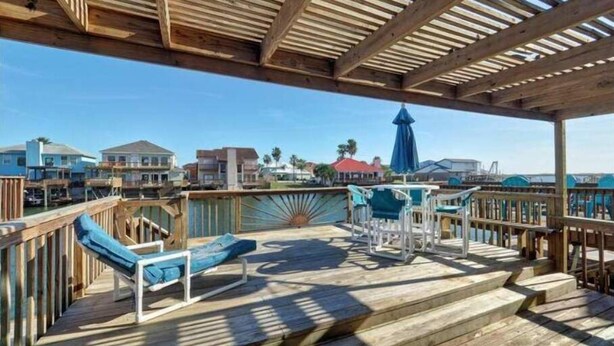 A wooden deck with steps leading to a seating area, overlooking a coastal town. - Relaxing Waterfront Home on Laguna Madre- Near Beach with Kayaking and Nature (Corpus Christi)