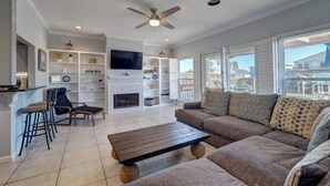 A spacious living room with a large sofa, a coffee table, a fireplace, and a TV mounted on the wall. - Relaxing Waterfront Home on Laguna Madre- Near Beach with Kayaking and Nature (Corpus Christi)