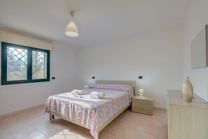 Une chambre à coucher comprenant un lit, des tables de chevet, une commode, une fenêtre et une coiffeuse.