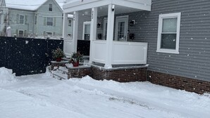 A two-story house with a porch, an American flag, and a wreath.