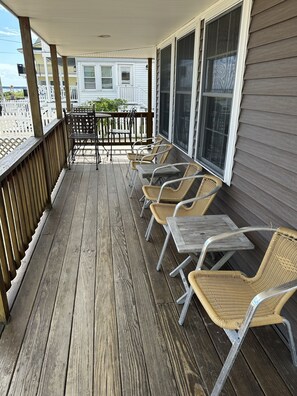 A wooden deck with wicker chairs and tables, overlooking a residential area. - 4 Bedroom Oceanfront Cottage on Old Orchard Beach (Old Orchard Beach)