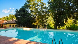 A swimming pool with a brick deck, surrounded by trees and a building. - Tuscan Sun Duplex with Balcony and Shared Pool, Radicondoli, Italy (Radicondoli)