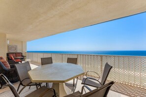 A balcony with a table and chairs, a sofa, and a view of the ocean. - Regency Towers Penthouse #1409 (Panama City Beach)