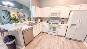 A modern kitchen with white cabinetry, a built-in microwave, an oven, and a refrigerator. - Modern Home w/Pool close to Disney Florida theme parks (Kissimmee)