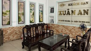Una habitación con un sofá de madera tradicional, una mesa con superficie de vidrio y cuadros en la pared.