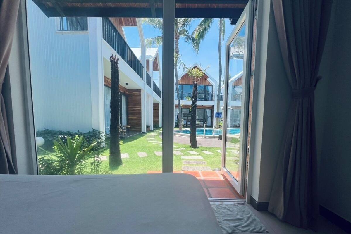 A hotel room with a bed, large windows, and a view of a pool and outdoor area.