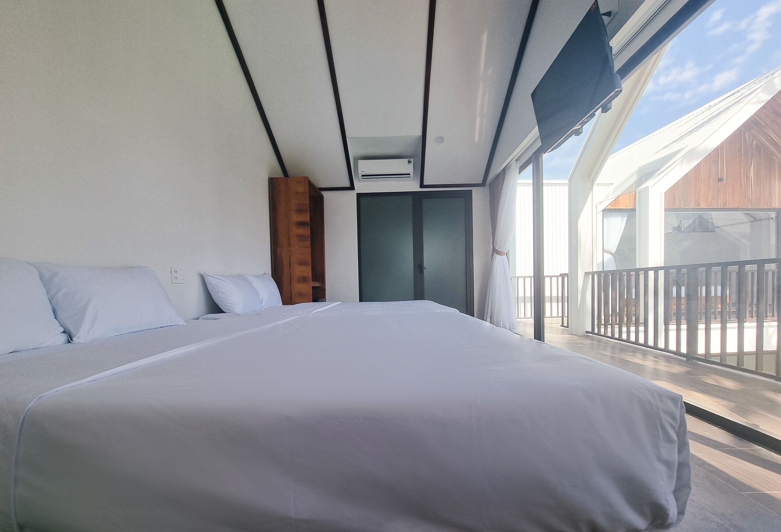Quarto moderno com uma cama grande, um guarda-roupa de madeira e uma varanda com grades.