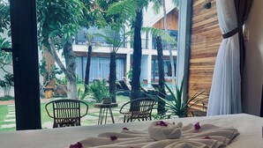 Habitación de hotel con cama, vista a una piscina y mobiliario exterior, y una pared de madera.