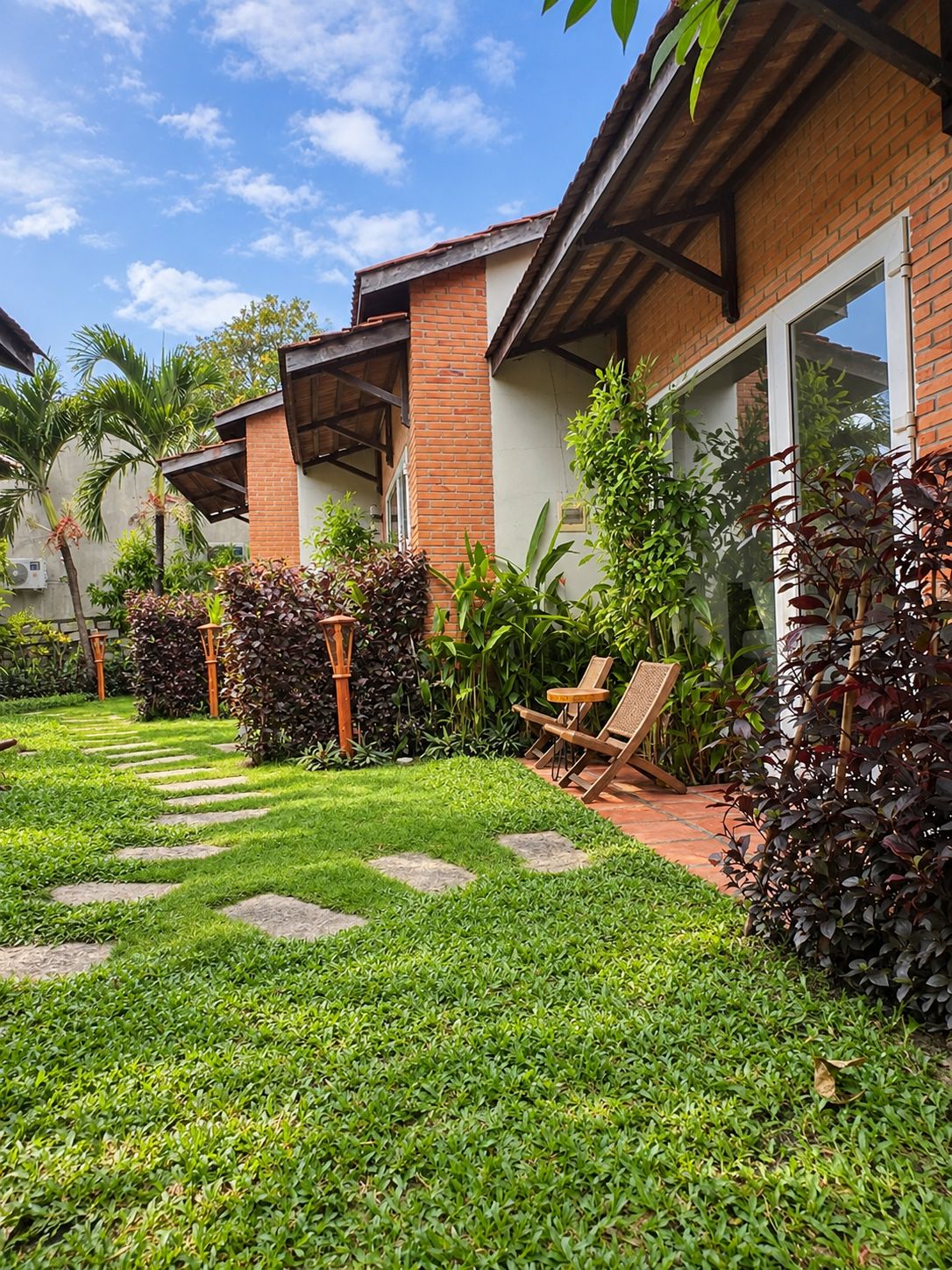 A well-maintained garden with a pathway leading to a building with a brick facade and large windows.