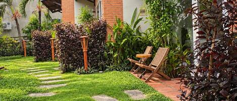 A well-maintained garden with a pathway leading to a building with a brick facade and large windows.