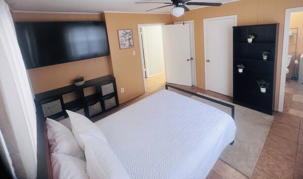 A bedroom with a bed, a ceiling fan, a wardrobe, and a door leading to another room. - Whole House-Near Airport, Beaches & Downtown Savannah (Savannah)
