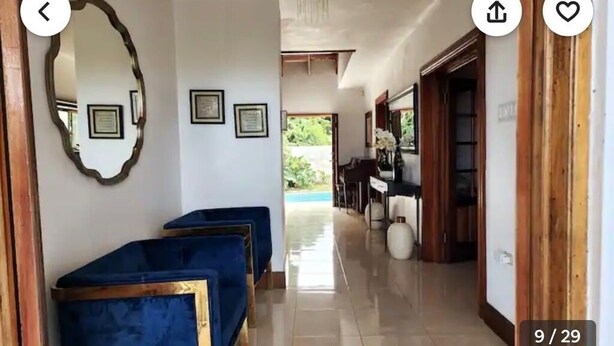 Ein Flur mit blau gepolsterten Stühlen, gerahmten Zertifikaten an der Wand und Blick auf einen Poolbereich.