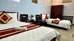 A hotel room with two beds, a wooden wardrobe, a small table with a plant, and a painting on the wall. - Thien Phuoc Hotel - by Bay Luxury (Ho Chi Minh City)