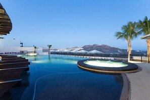Une piscine offrant une vue sur les montagnes, les palmiers et un bâtiment moderne.