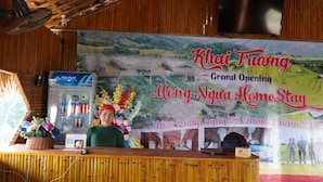A reception desk with a banner for Khai Trawng Grand Opening, a water dispenser, and a floral arrangement. - MONG NGUA BUNGALOW & HOMESTAY (Thong Nguyen)