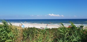 Une plage avec des gens, un drapeau et un ciel dégagé.