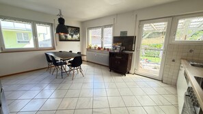 A kitchen with a dining table, chairs, a radiator, and a view through the door.