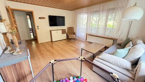 A living room with a sofa, a coffee table, a TV, and a trampoline.