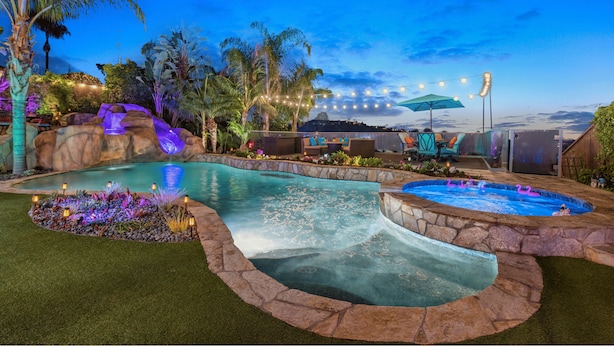 Un espace piscine aménagé avec une cascade, un jacuzzi et un coin salon.
