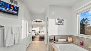 Une salle de bain d’hôtel moderne, dotée d’une grande baignoire, d’un ventilateur de plafond et d’une pancarte indiquant « DÉTENTE ET RELAXATION ».
